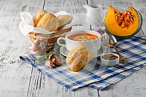 Pumpkin soup in a bowl with fresh pumpkins, garlic and parsley h