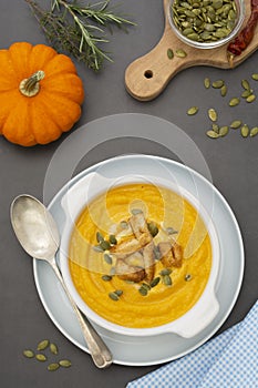 Pumpkin soup in a bowl,with fresh pumpkin seeds. Autumn foods. Healthy, vegetarian food, flat lay dark background