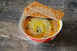 Pumpkin soup with bread on a wooden tabletop, side view