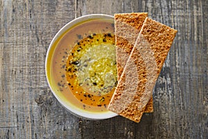 Pumpkin soup with bread on a wooden tabletop, top view