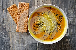 Pumpkin soup with bread on a wooden tabletop, top view