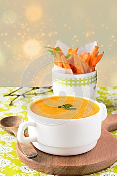 Pumpkin soup with carrot chips on a wooden stand