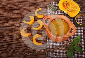 Pumpkin soup in clay pot with fresh pumpkins