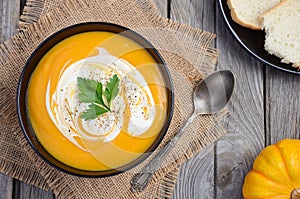 Pumpkin soup with cream and parsley on wooden background