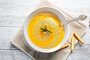 Pumpkin soup with linen napkin on light background.