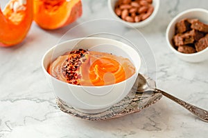 Pumpkin soup and organic pumpkins on marble table. Seasonal autumn food - Spicy pumpkin and carrot soup