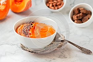 Pumpkin soup and organic pumpkins on marble table. Seasonal autumn food - Spicy pumpkin and carrot soup