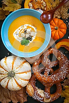 Pumpkin soup.Seasonal dishes .Soup decorated with pumpkin leaves and pretzels .Autumn