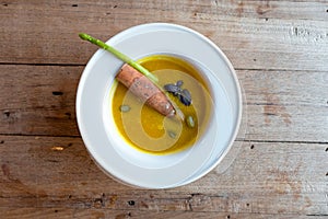 Pumpkin soup with seed and cinnamon stick in white round bowl.