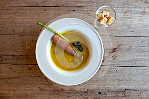 Pumpkin soup with seed and cinnamon stick in white round bowl.