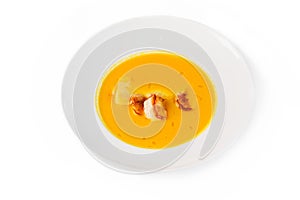 Pumpkin soup with shrimps in a plate on white background. Top view, close-up