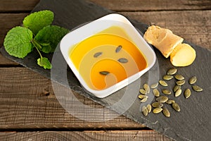 pumpkin soup in a soup bowl with ginger, pumpkin seeds and mint