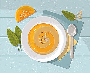 Pumpkin soup with spoon on blue  background. Top view.