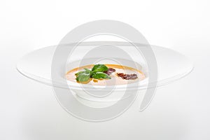 Pumpkin soup on white plate isolated