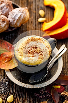 Pumpkin spice latte, coffee with the addition of pumpkin puree, aromatic spices,  sprinkled with cinnamon  in a cup on a wooden ta