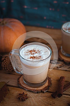 Pumpkin spice latte in glass cups, on wooden background