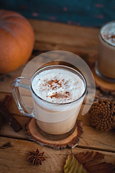 Pumpkin spice latte in glass cups, on wooden background