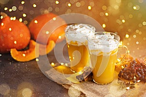 Pumpkin spice latte in a glass mug with cinnamon and whipped cream. Bokeh background. Autumn, winter drinks. Holiday drinks.