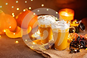 Pumpkin spice latte in a glass mug with cinnamon and whipped cream. Dark background. Autumn, winter drinks. Holiday drinks.