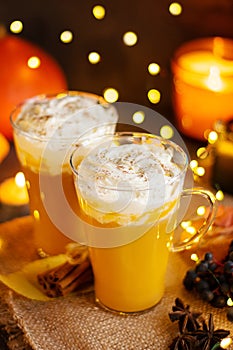 Pumpkin spice latte in a glass mug with cinnamon and whipped cream. Dark background. Autumn, winter drinks. Holiday drinks.