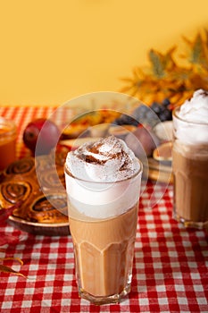 Pumpkin spice whipped latte in glass. Hot autumn drink beverage. Nearby delicious pie and appetizers fruits and cheese