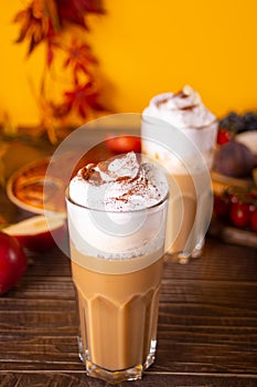 Pumpkin spice whipped latte in glasses. Hot autumn drink beverage. Nearby delicious pie and appetizers fruits and cheese