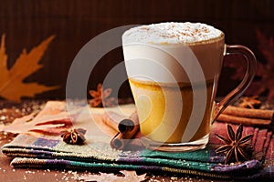 Pumpkin spiced latte or coffee in a glass on a rustic table. Autumn or winter hot drink.