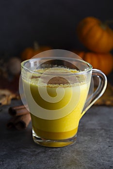 Pumpkin spiced latte macchiato on a dark wooden background autumn drink beverage golden milk