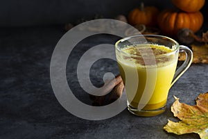 Pumpkin spiced latte macchiato on a dark wooden background autumn drink beverage golden milk with copy space