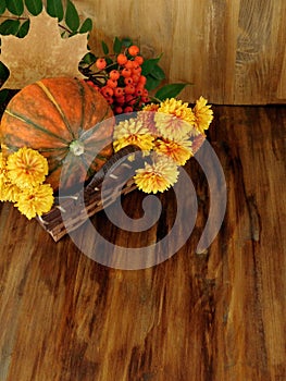 Pumpkin in a wicker basket with flowers, rowan and dry leaves