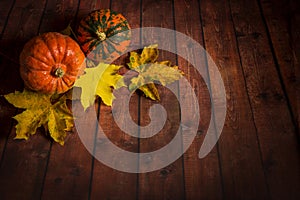 Pumpkin on wooden background with maple leaves .