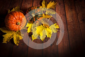 Pumpkin on a wooden background with maple leaves