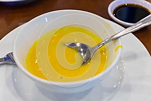 Pumpkin yellow soup in a plate with a spoon on the table