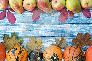 Pumpkins, apples, pears and autumn leaves on wooden background.