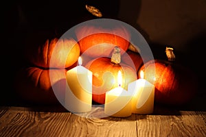 Pumpkins and burning candles on a wooden background