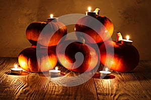 Pumpkins and burning candles on a wooden background