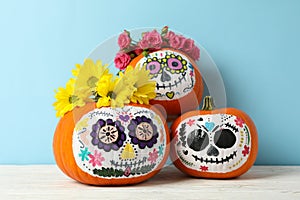 Pumpkins with catrina skull makeup and flowers on blue background