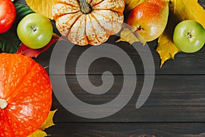 Pumpkins with colorful maple leaves, ripe apples and pear on dark wooden background. Autumn seasonal image with free space for you