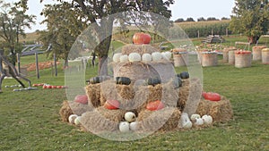 Pumpkins decorate bales of straw in the field. Children play in the countryside.