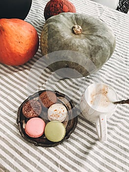 Pumpkins, hot coffee and macaroons on vintage plate on rustic table. Autumn morning. Fall decor on rustic table