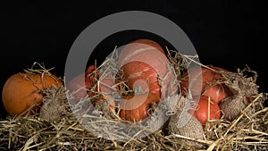 Pumpkins and a jute bag in straw on a black background
