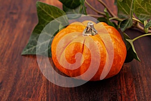 Pumpkins and leaves over wooden background with copy space