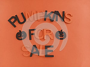 Pumpkins for sale sign with orange and black letters