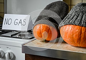 Pumpkins in winter knit hats on Halloween at cold home, expensive gas and electricity for heating