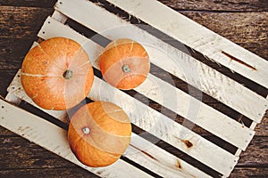 Pumpkins wooden background lie on vegetable box.