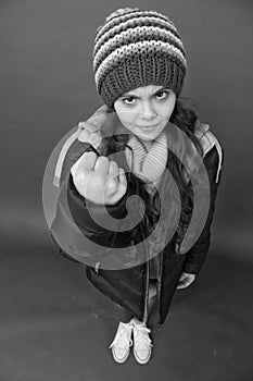 Punch in face. Threatening fist. Little girl wear winter clothes red background. Childhood concept. Emotional girl long