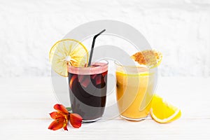 Punch and orange juice glasses on white background