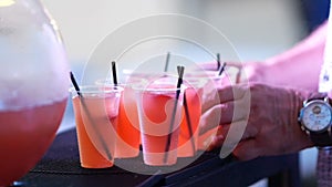 Punch in plastic cups with tubes on the bar in a nightclub. visitors take the glasses.