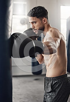 Punching bag, boxing and boxer man in workout training or exercise in a gym. Strong, powerful and serious athlete or