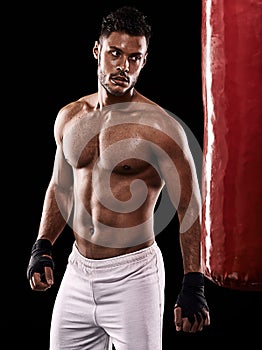 Punching bag, man and boxing with fitness, training for a competition and wellness on a dark studio background. Person